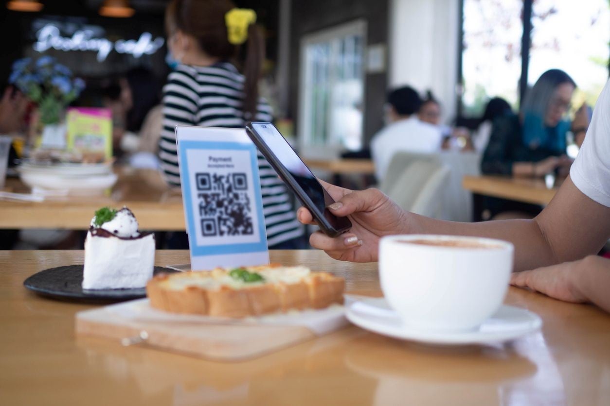 Cliente escaneando um QR code em um café para realizar o pagamento digital. Cliente escaneando um QR code em um café para realizar o pagamento digital.