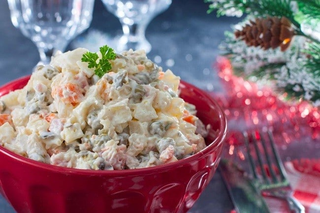 Mesa de natal, com enfeite de centro de mesa e salada de batata com maionese em destaque.