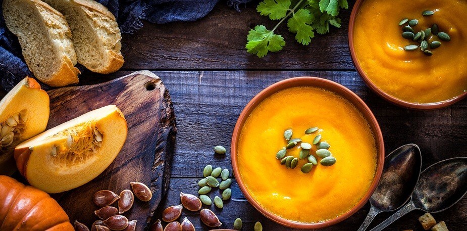 Sopa de abóbora com sementes servida em uma mesa rústica. Sopa de abóbora com sementes servida em uma mesa rústica.