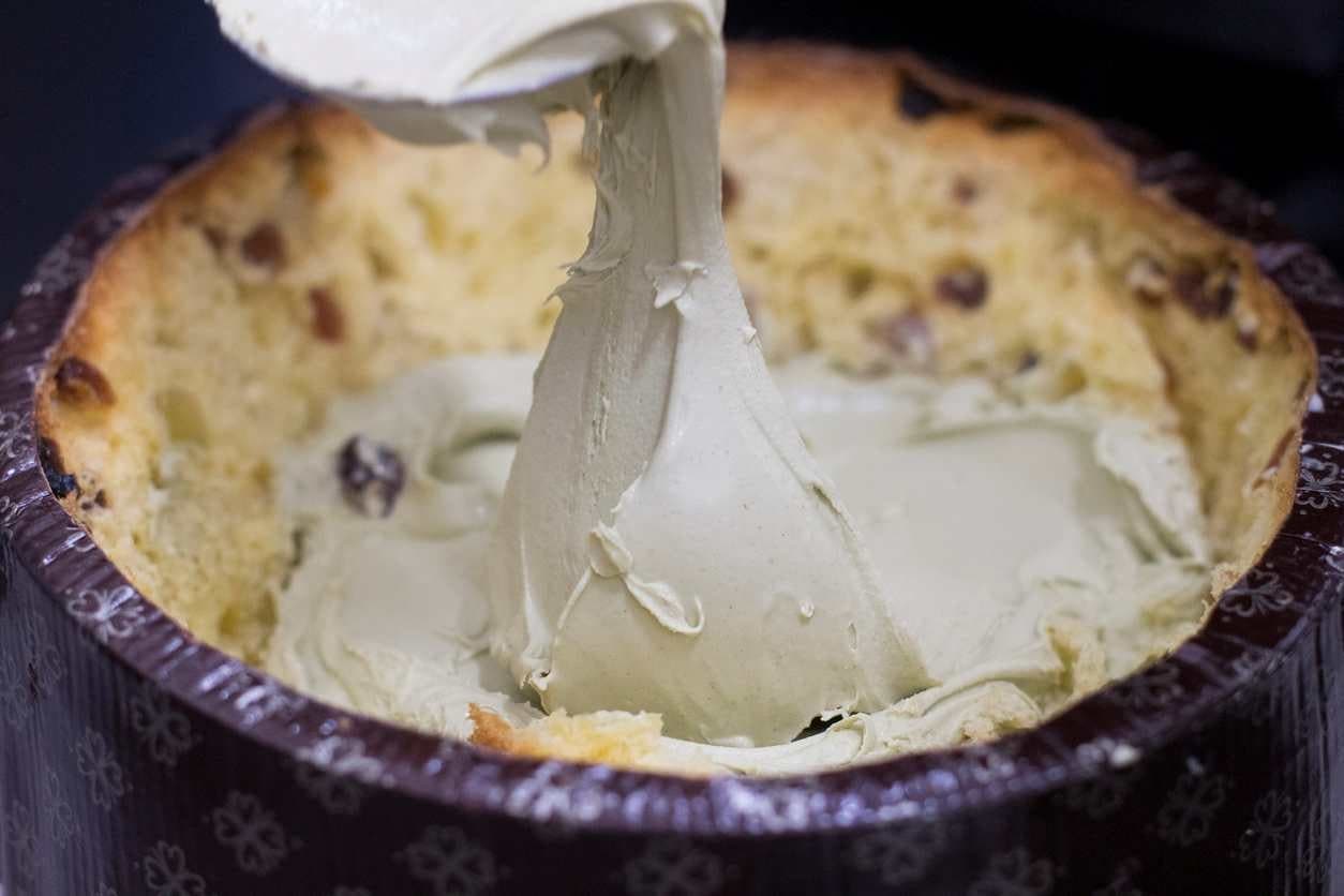Panetone aberto, sendo recheado com sorvete de creme.