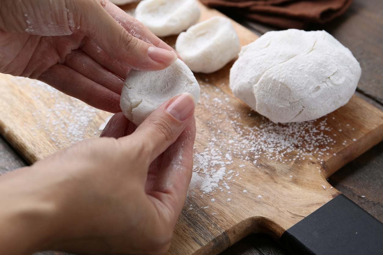 Mulher preparando a massa do mochi sobre uma tábua de madeira