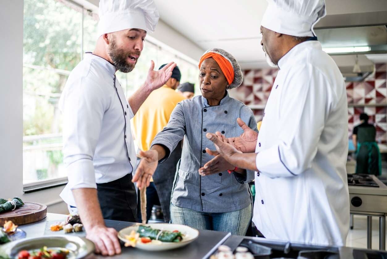 Três colaboradores discutindo em ambiente de trabalho. A situação parece difícil Três colaboradores discutindo em ambiente de trabalho. A situação parece difícil