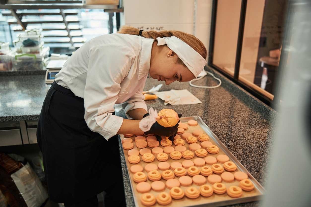 Chef pâtissier recheando macarons feitos sob medida