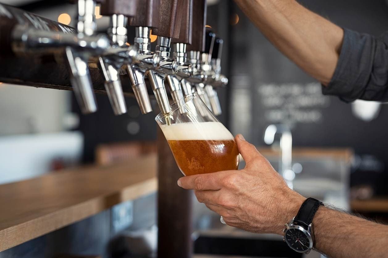 Garçom tirando chope com um belo colarinho.