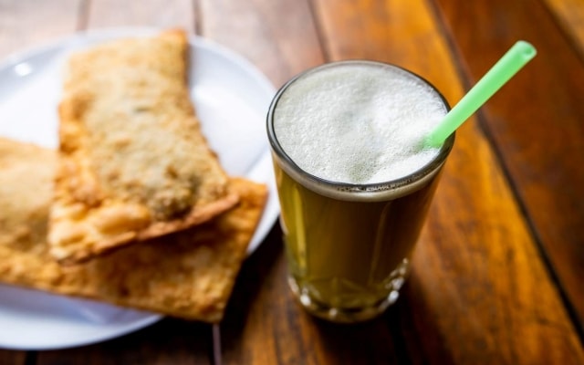 Copo de caldo de cana com alguns pasteis ao fundo. Copo de caldo de cana com alguns pasteis ao fundo.