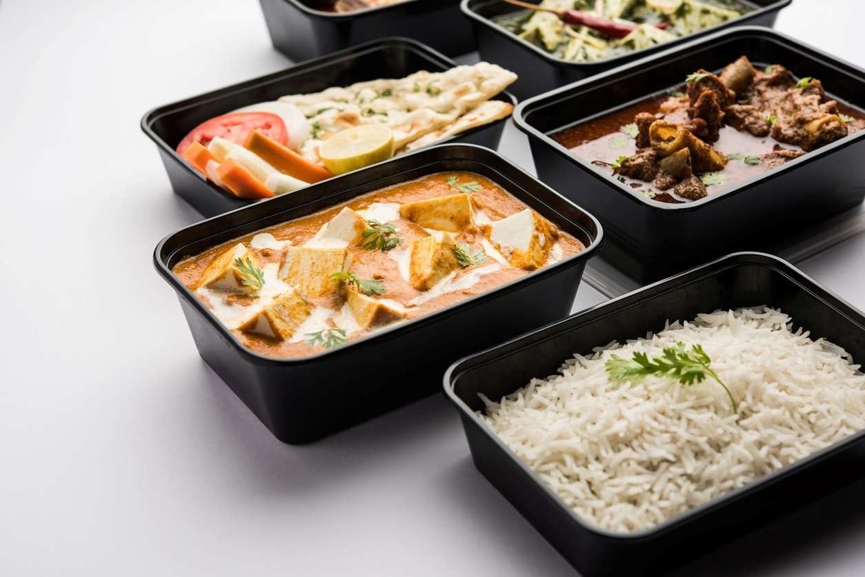 Embalagens de delivery com pratos variados dispostas em fundo claro, ilustrando a importância de boas fotos para o iFood.