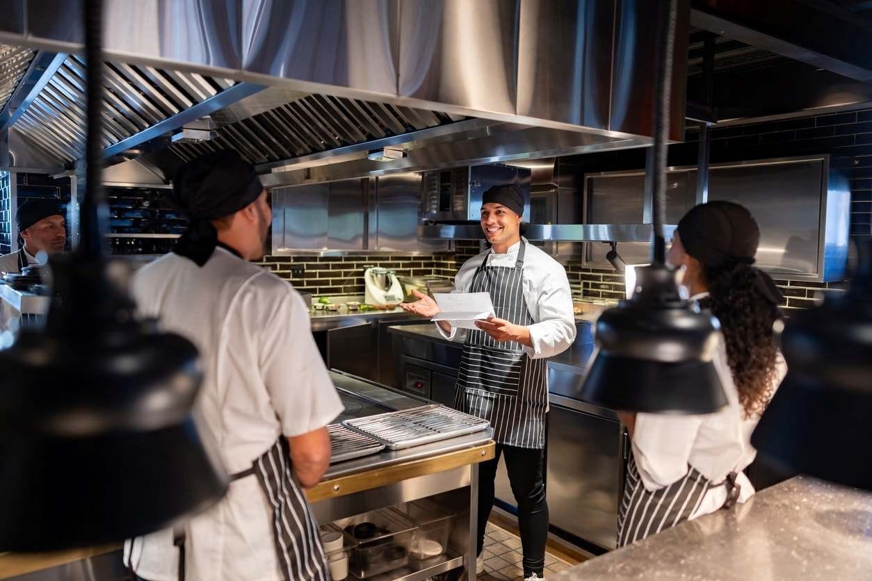 Chef explicando algo ao seu time de cozinha.