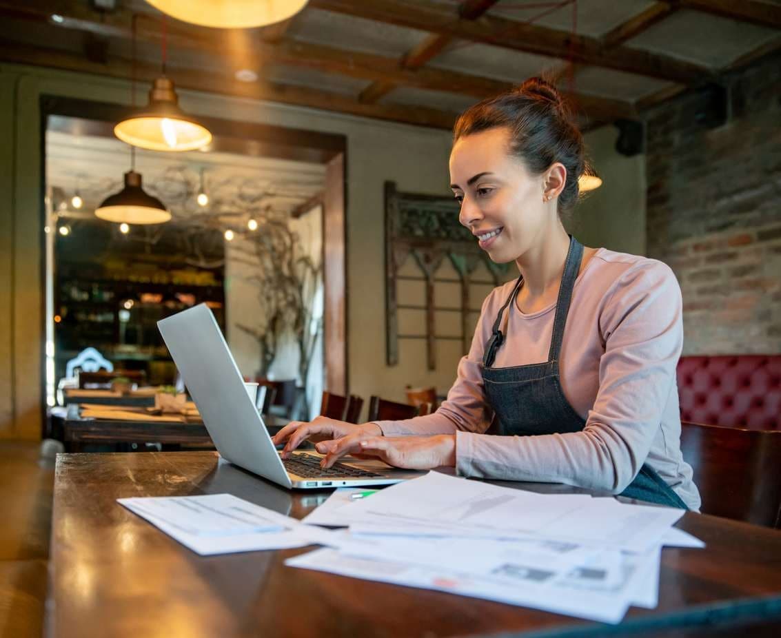 Empresária fazendo a contabilidade do seu restaurante em seu laptop