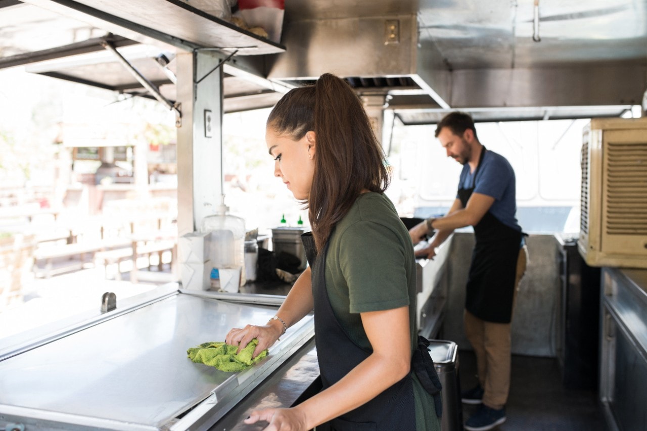 Mulher e homem limpando seu food truck, preparando tudo para receber seus clientes. Mulher e homem limpando seu food truck, preparando tudo para receber seus clientes.