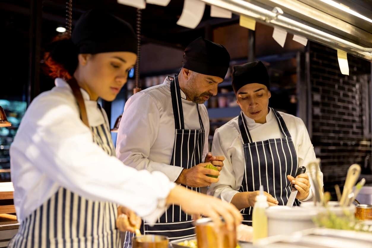 Profissionais de cozinha montando pratos sofisticados. Pela iluminação, sabe-se que já é noite. Profissionais de cozinha montando pratos sofisticados. Pela iluminação, sabe-se que já é noite.