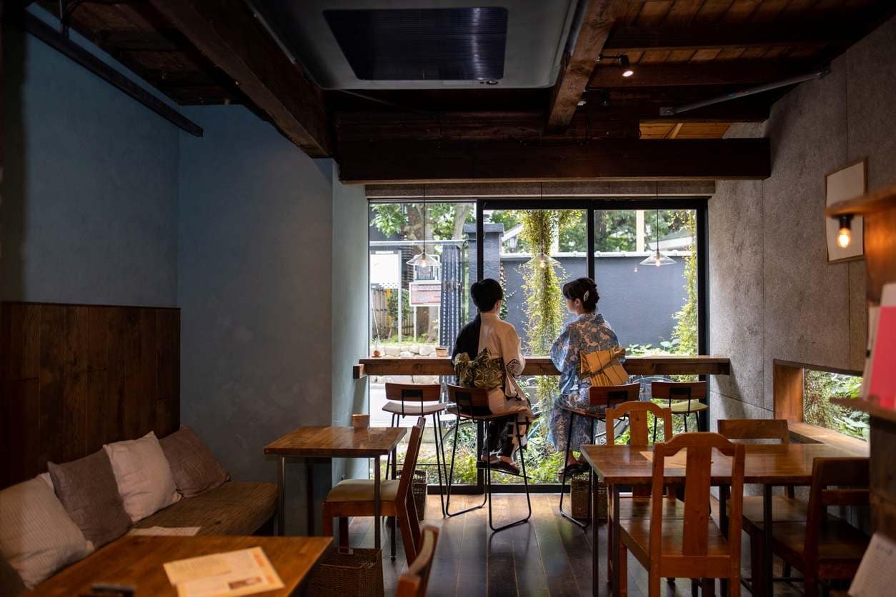 Duas mulheres em um café de decoração minimalista, usando vestes tradicionais japonesas.