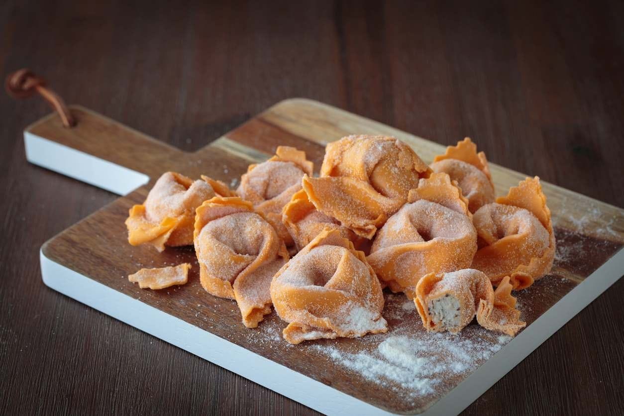 Tortellini em uma tábua de madeira pronto para ser cozido