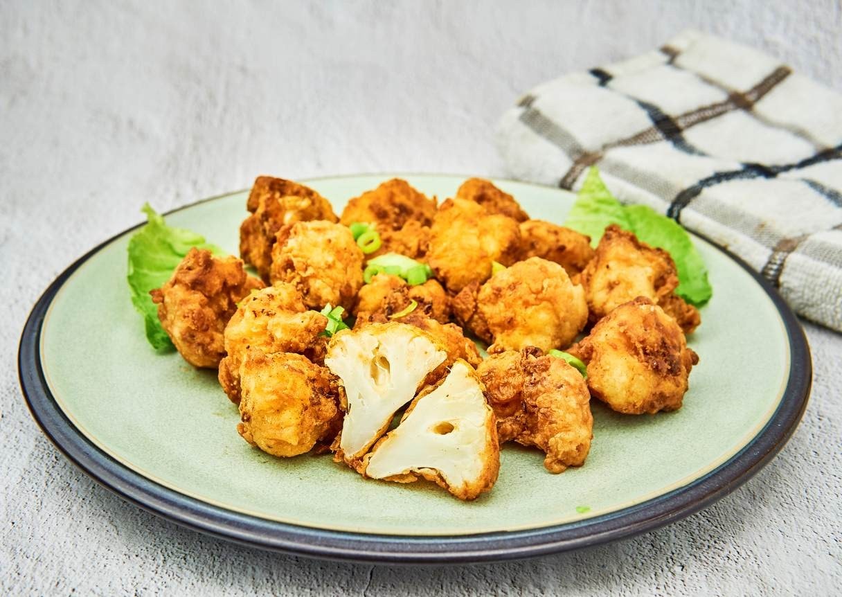 Prato com couve-flor a milanesa. Uma delas está cortada ao meio.