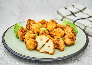 Prato com couve-flor a milanesa. Uma delas está cortada ao meio.
