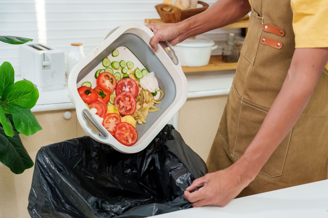 Pessoa despejando restos de alimentos no lixo. Pessoa despejando restos de alimentos no lixo.