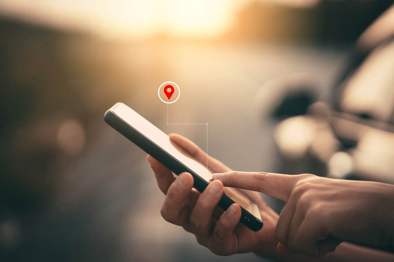 Mão segurando smartphone com ícone de localização, representando o uso do Google Meu Negócio para aumentar a visibilidade local de restaurantes.