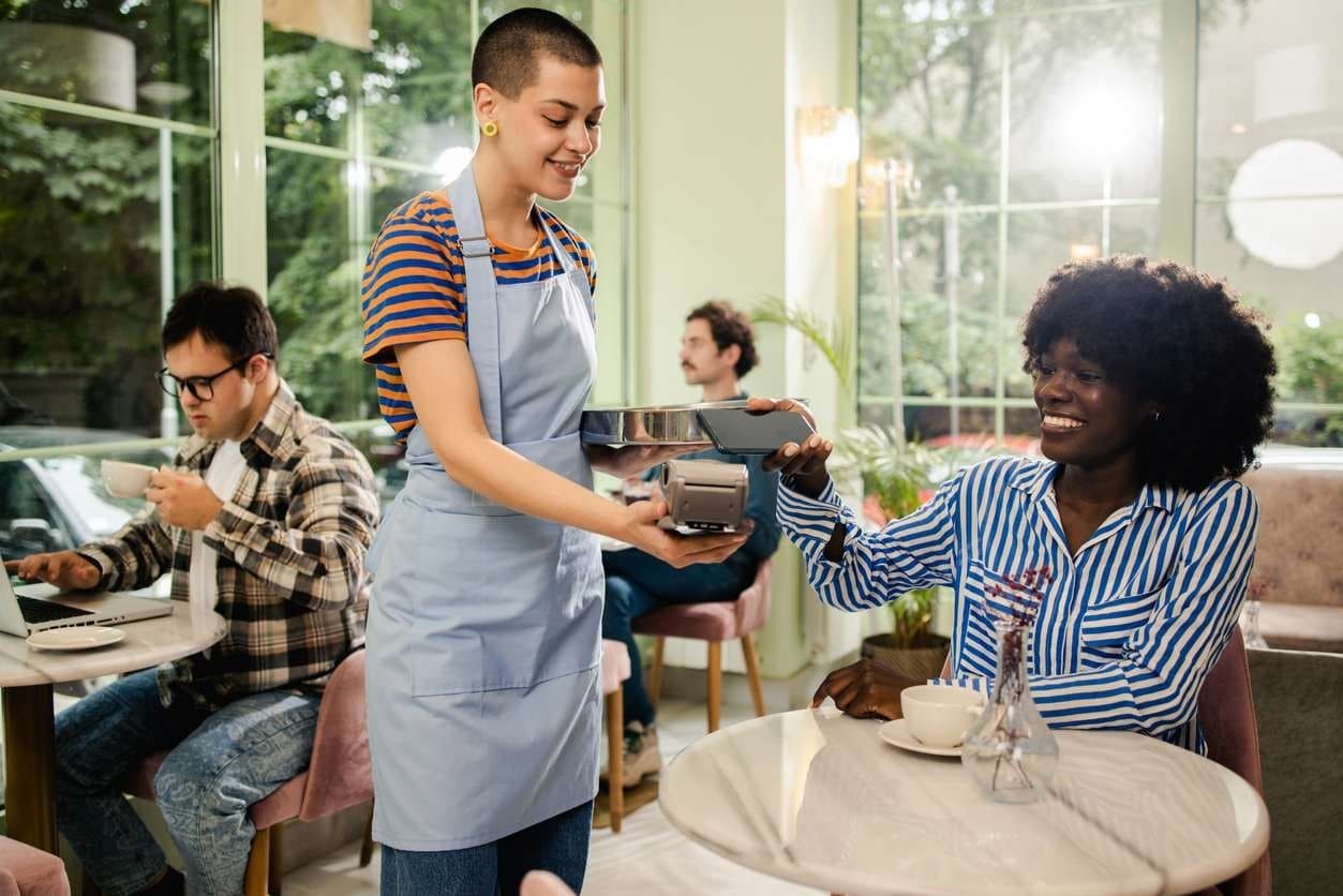 Cliente pagando sua conta em um restaurante, diretamente para quem lhe atendeu na mesa