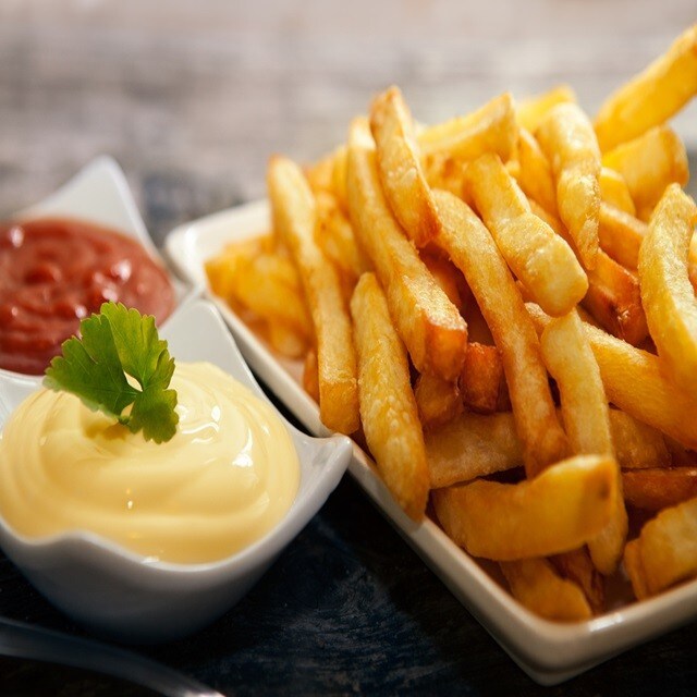 Porção de batata frita, ao lado de potes com maionese e ketchup. Porção de batata frita, ao lado de potes com maionese e ketchup.