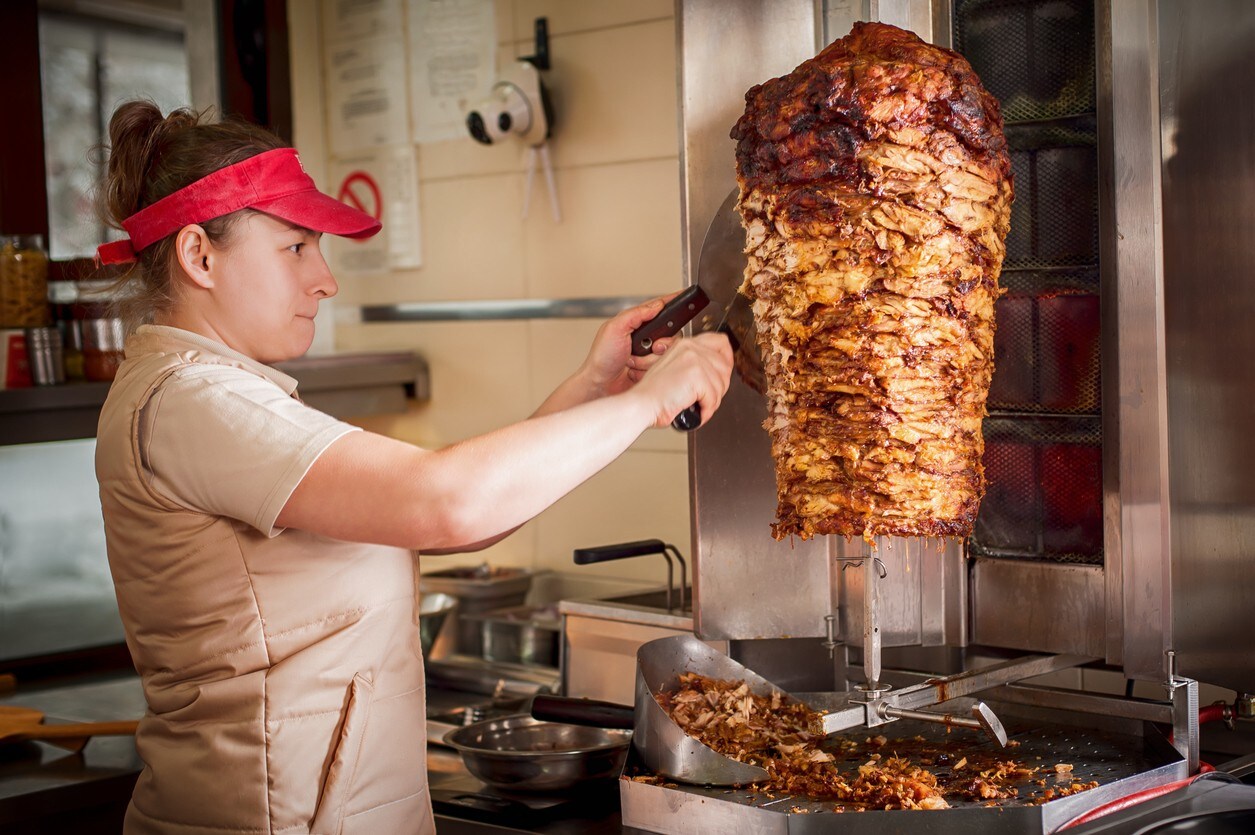 Mulher servindo generosas fatias de carne para montar um delicioso churrasco grego. Mulher servindo generosas fatias de carne para montar um delicioso churrasco grego.