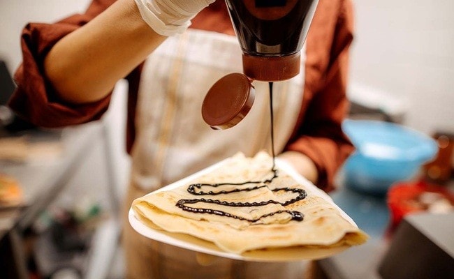 Crepe francês recebendo cobertura de chocolate Crepe francês recebendo cobertura de chocolate