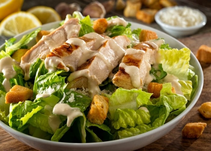 Prato de salada caesar bem servida, com mix de folhas, queijo parmesão ralado, molho e tiras de frango, além do crouton Prato de salada caesar bem servida, com mix de folhas, queijo parmesão ralado, molho e tiras de frango, além do crouton