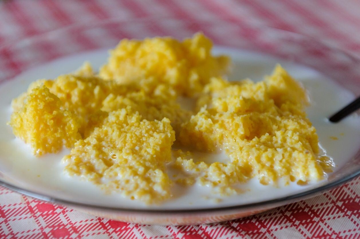 Prato de cuscuz com leite servido em uma mesa com toalha xadrez. Prato de cuscuz com leite servido em uma mesa com toalha xadrez.