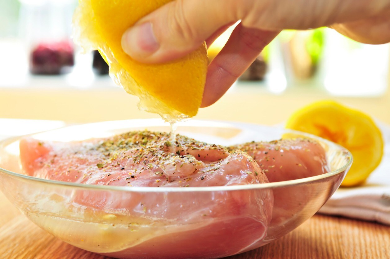 Alguém está colocando limão em filés de frango, já com pimenta e outros temperos, para fazer marinada. Alguém está colocando limão em filés de frango, já com pimenta e outros temperos, para fazer marinada.