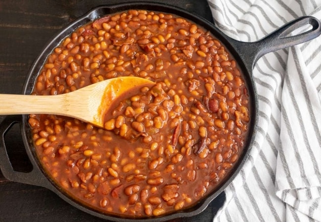 Detalhe de panela refogando feijão com temperos. 